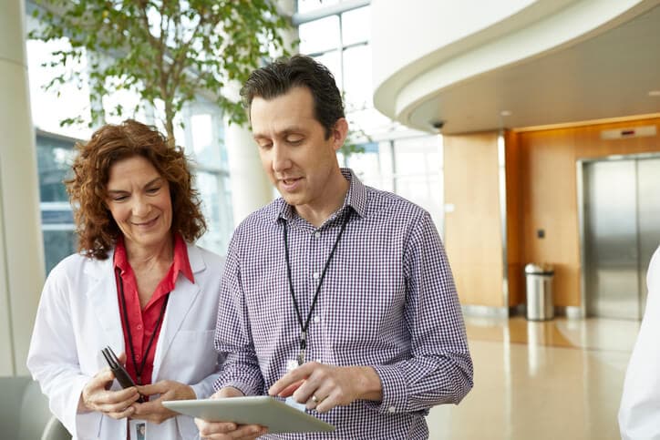 Senior healthcare administrator chatting with a staff doctor while standing in a hospital lobby.