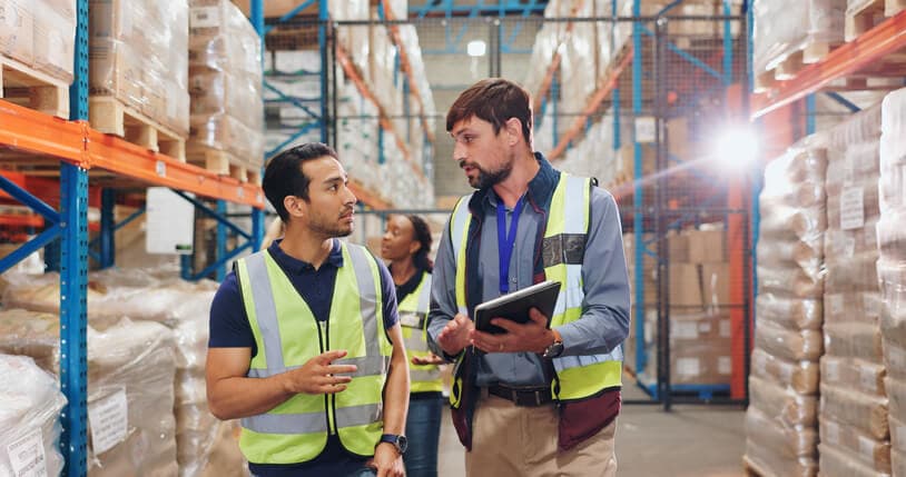 Two project managers discussing shipping inventory at a warehouse.