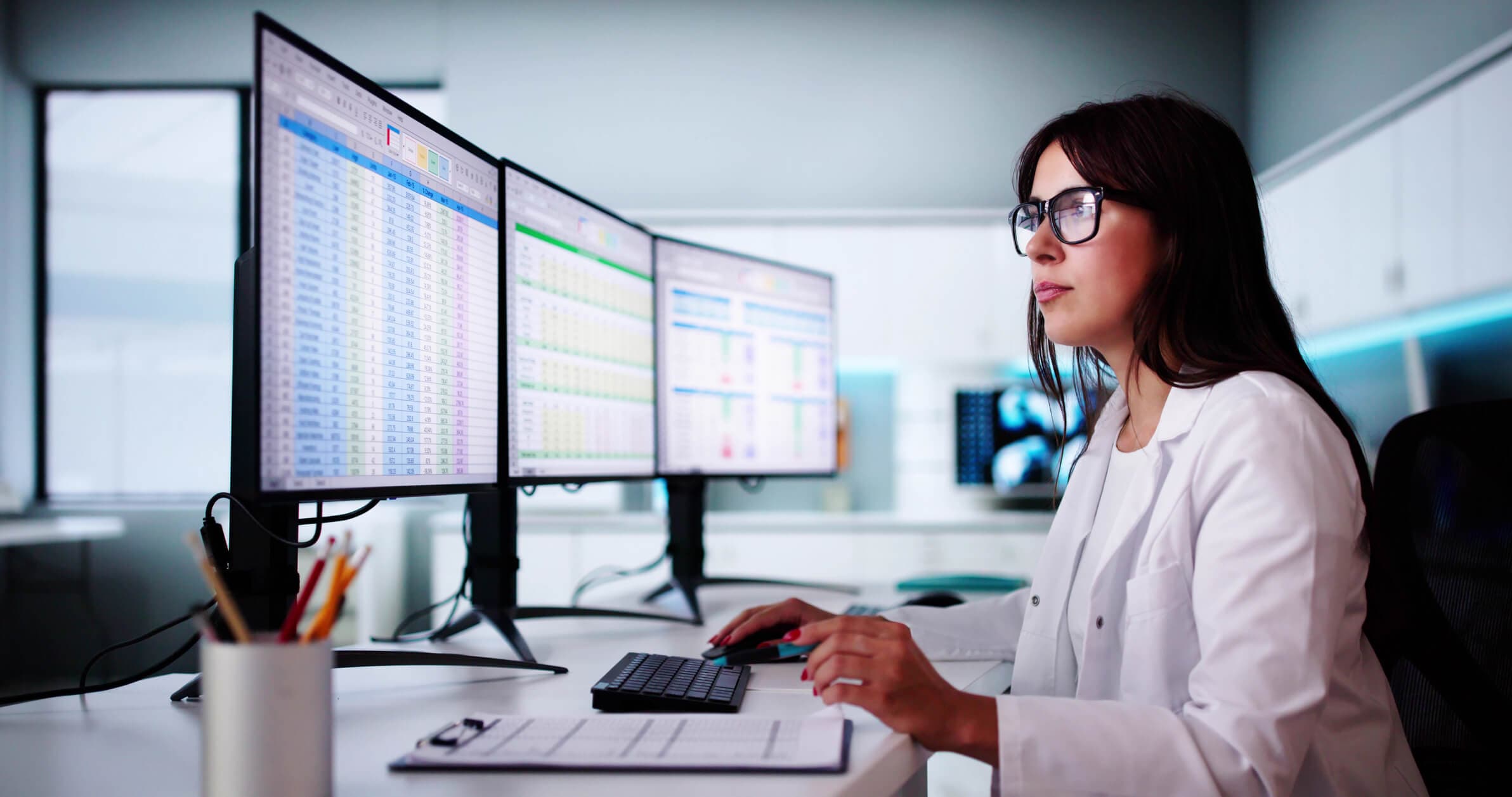 Medical data analyst editing a spreadsheet on her desktop computer at work.