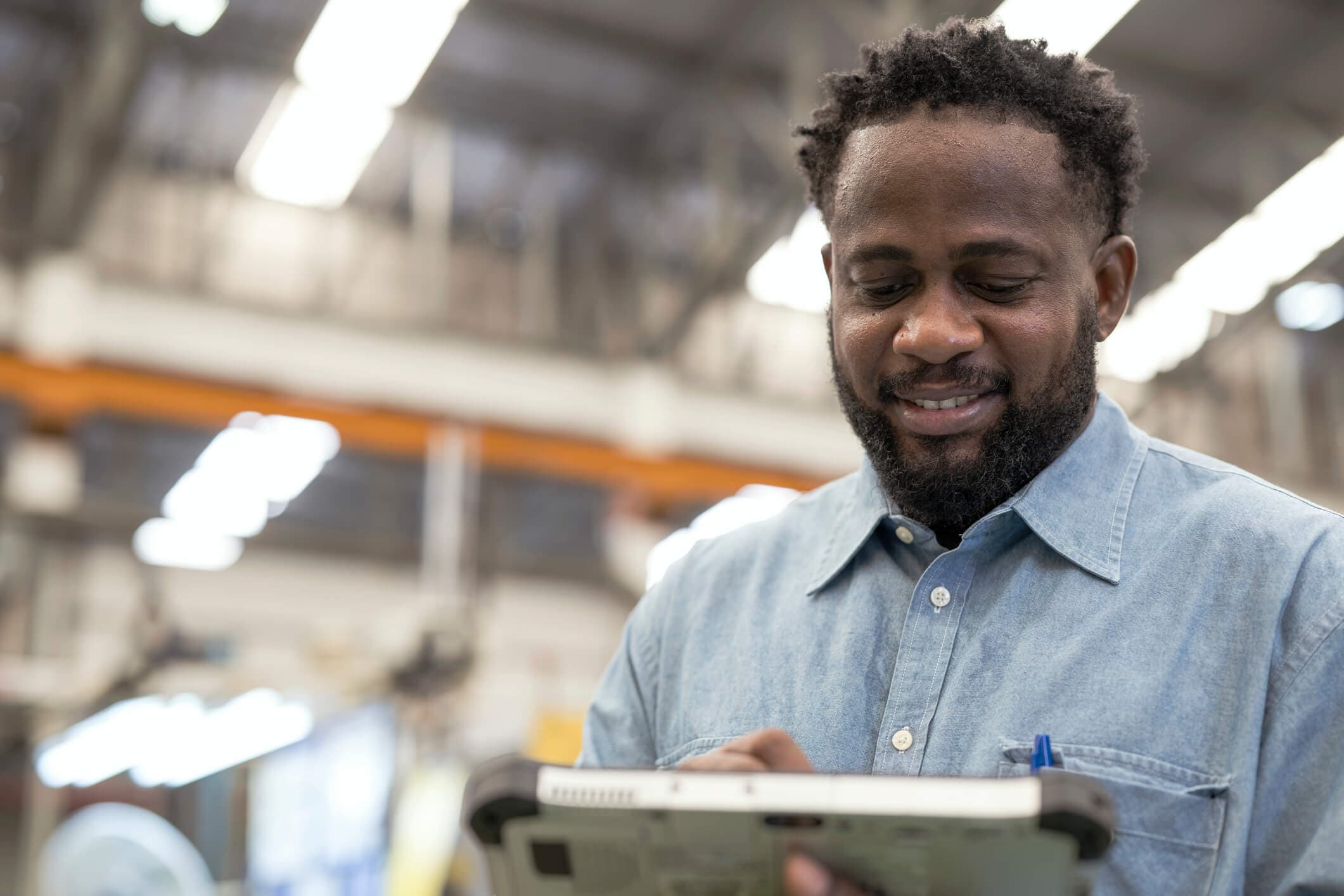 Black male supply chain manager using a digital tablet in the production line for recording factory production data.