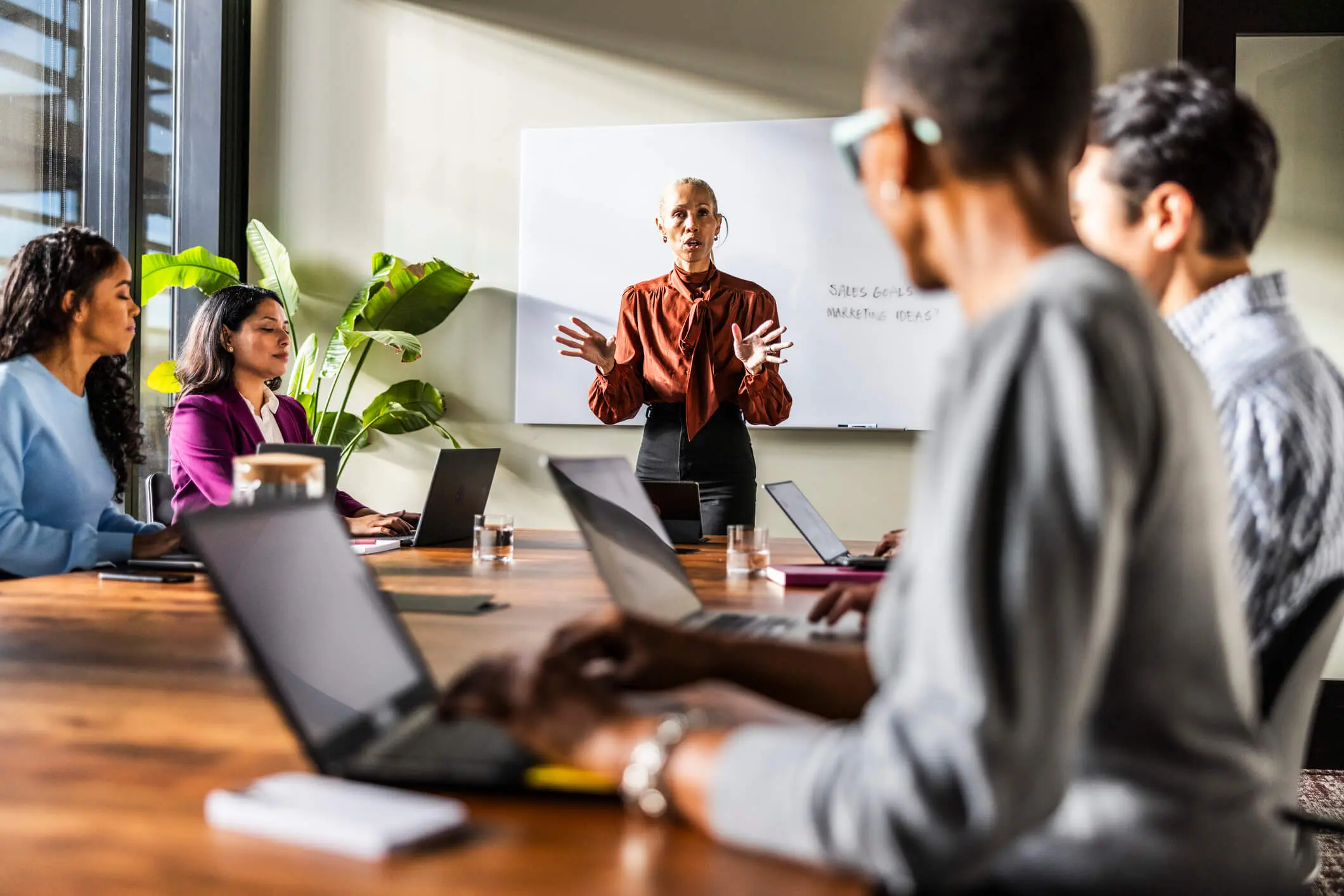 Female business owner speaking to office workers in a modern conference room.