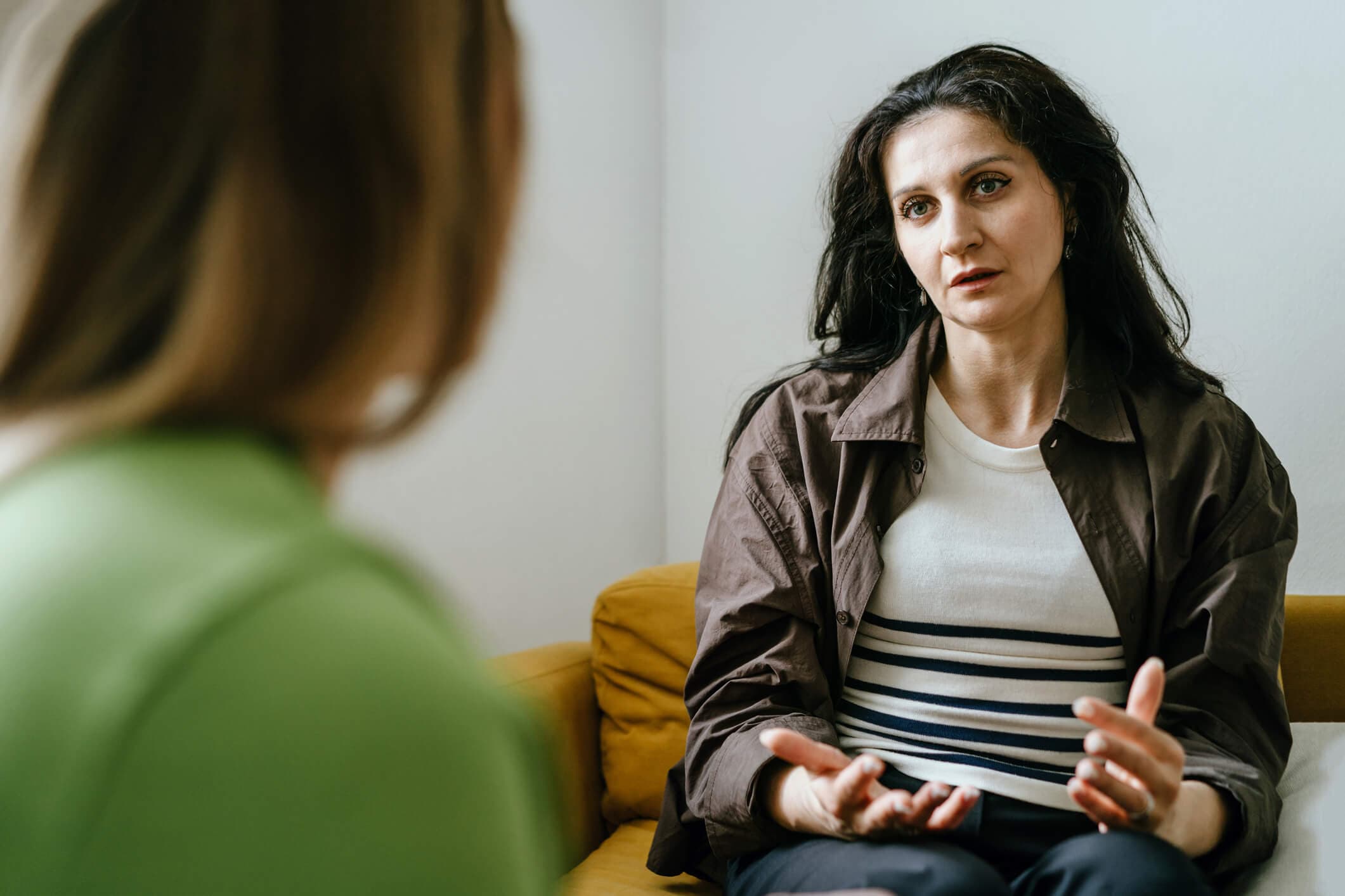 Senior female psychologist talking with her female patient in her office.