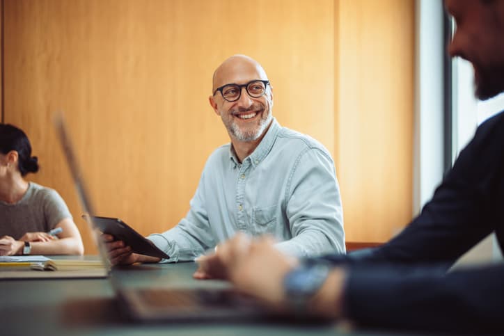Senior male business manager smiling during a meeting with colleagues in the office board room.