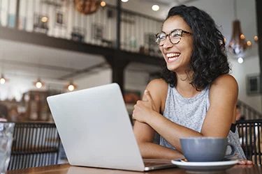 Woman laughing and looking up from laptop