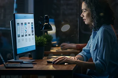 Woman looking intently at two computer monitors