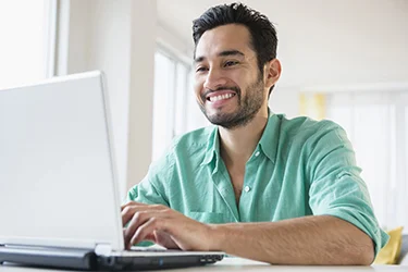 Bearded man smiling and looking at laptop